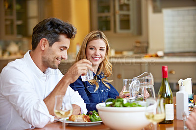 Buy stock photo Shot of a young couple enjoying a home-cooked dinner together