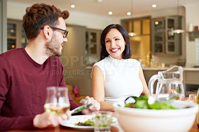 Buy stock photo Shot of a young couple enjoying a home-cooked dinner together