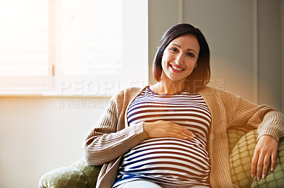 Buy stock photo Portrait of a smiling pregnant woman sitting on her sofa