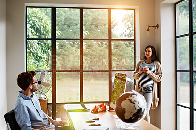 Buy stock photo Shot of a pregnant woman and her husband talking together in their home office
