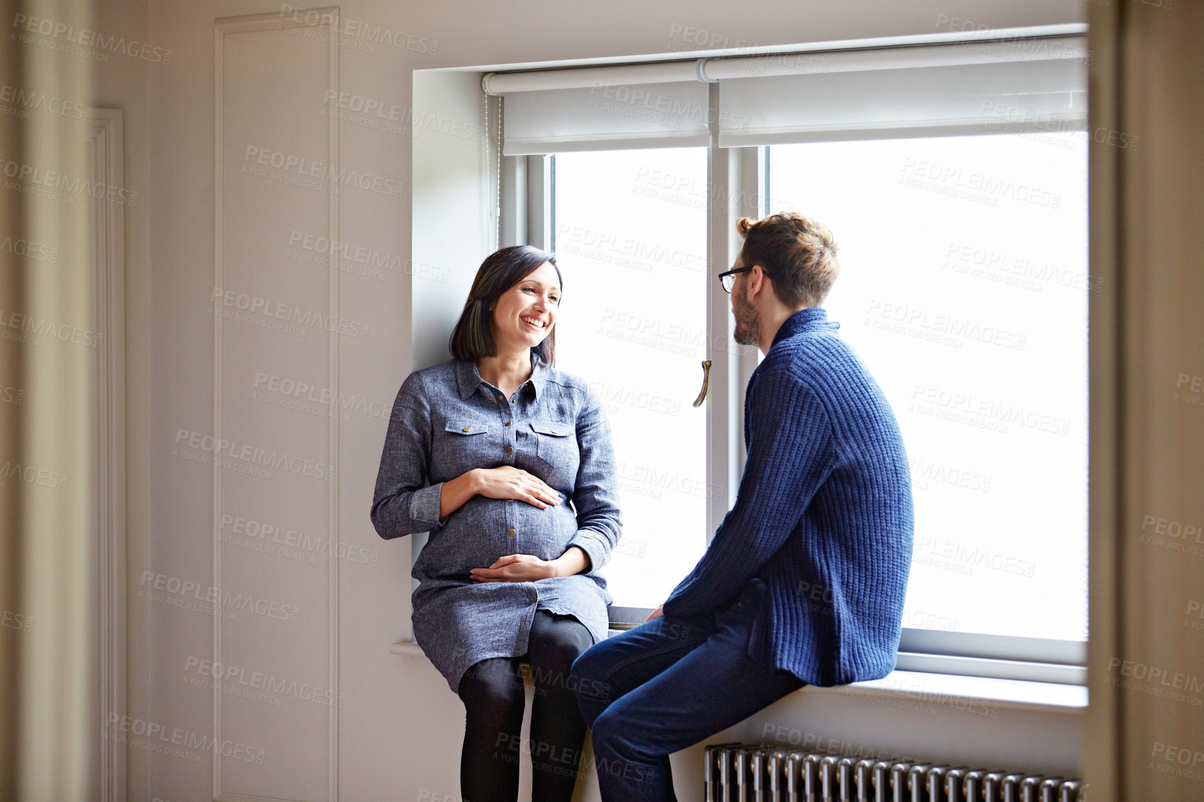 Buy stock photo Pregnancy, smile and wife with husband at window in home together for bonding, support or wellness. Baby bump, happy and pregnant woman with man in apartment for development, love or security