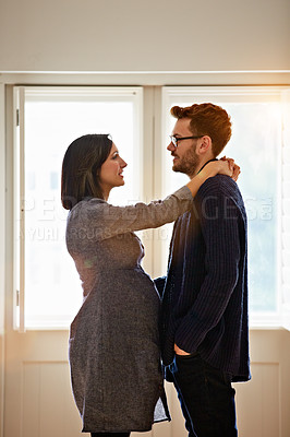 Buy stock photo Shot of a happy pregnant couple standing face to face together in their home