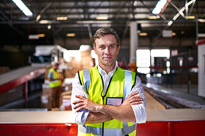 Buy stock photo Portrait of a worker standing with his arms crossed in a large warehouse full of boxes