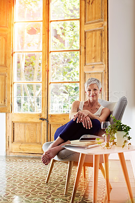 Buy stock photo Portrait of a smiling mature woman relaxing on a chair at home with a glass of wine