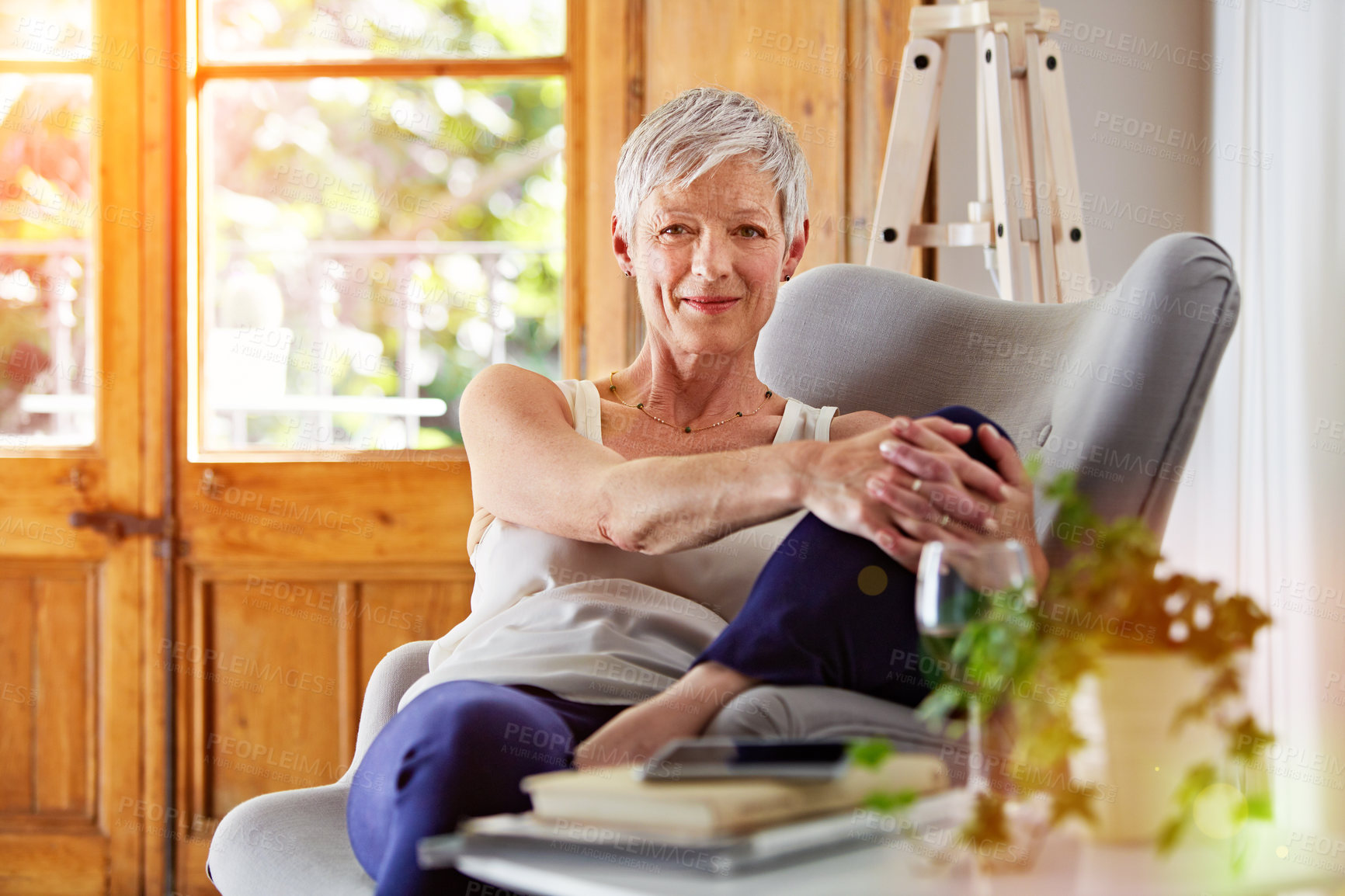 Buy stock photo Portrait of a smiling mature woman relaxing on a chair at home with a glass of wine