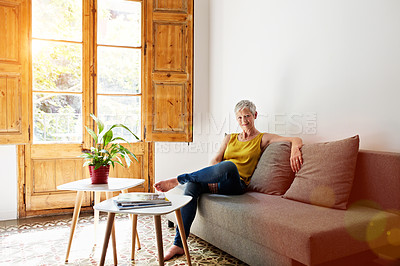 Buy stock photo Portrait of a smiling mature woman relaxing on her sofa at home