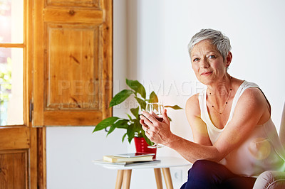 Buy stock photo Portrait of a smiling mature woman relaxing on a chair at home with a glass of wine