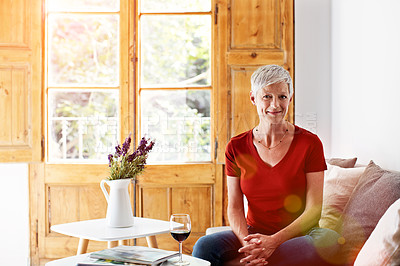 Buy stock photo Portrait of a smiling mature woman relaxing on a chair at home with a glass of wine