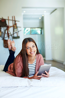 Buy stock photo Portrait of a young woman lying on her bed using a digital tablet