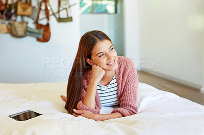 Buy stock photo Shot of a smiling young woman thinking while lying on her bed