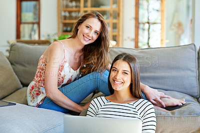 Buy stock photo Shot of two young friends sitting in a living room using a laptop together