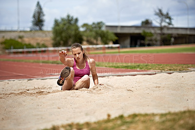 Buy stock photo Shot of a young woman landing in sand after a long jump