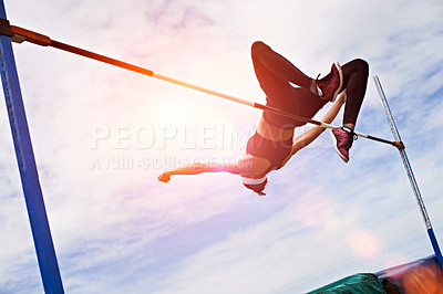 Buy stock photo Shot of a young woman in mid air doing a high jump on a sports field
