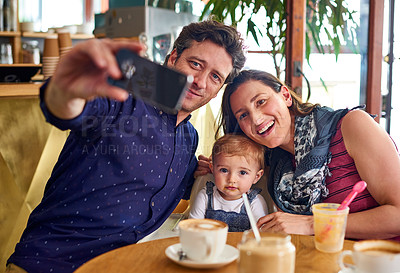 Buy stock photo Shot of a father taking a selfie with his wife and baby girl while sitting in a cafe