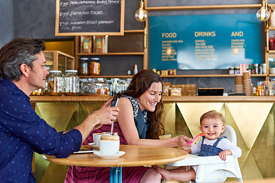Buy stock photo Shot of a couple and their baby daughter sitting at a table in a cafe