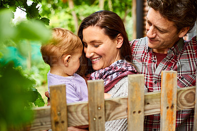 Buy stock photo Shot of a couple with their baby girl standing their organic garden