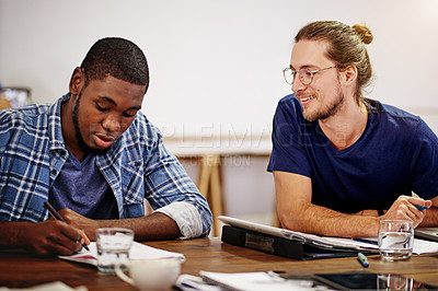 Buy stock photo Shot of two smiling colleagues talking together while sitting at a table in an office