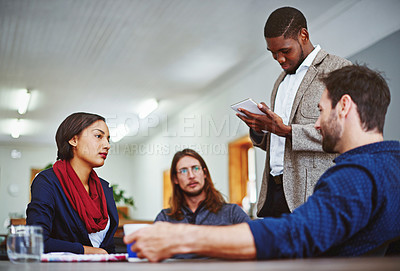 Buy stock photo Shot of a young man leading a meeting with coworkers in an office