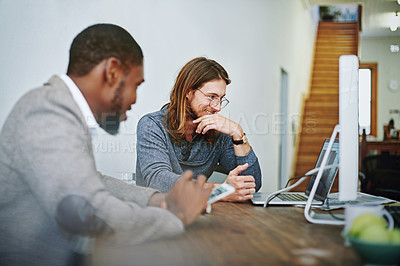 Buy stock photo Shot of two colleagues working together with a digital tablet and computer at a desk in an office