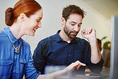 Buy stock photo Shot of two smiling colleagues talking together while while using a digital tablet in an office