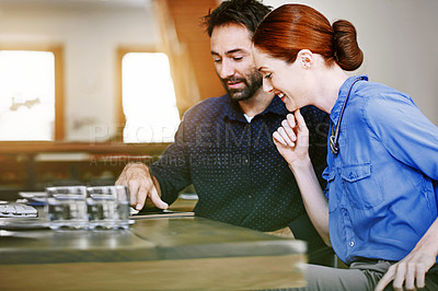 Buy stock photo Shot of two smiling colleagues talking together while sitting at a table in an office