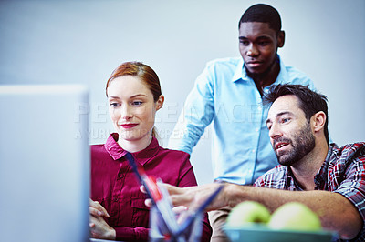 Buy stock photo Shot of a group of businesspeople working together on a laptop in an office