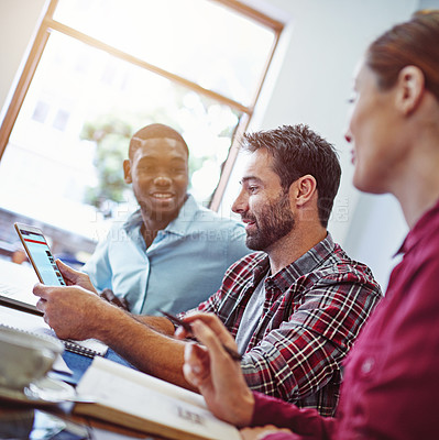 Buy stock photo Shot of a group of colleagues talking together over a digital tablet while sitting in an office