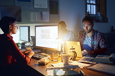 Buy stock photo Shot of a group of designers at work around a table in the evening