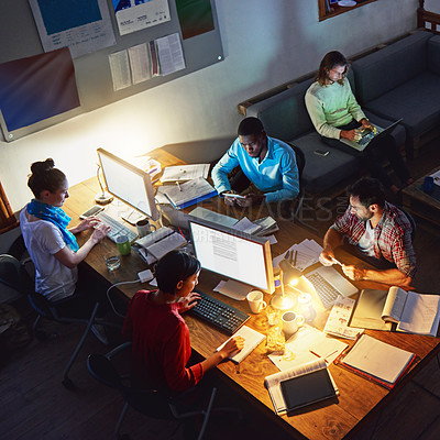 Buy stock photo High angle shot of a group of designers at work around a table in an office in the evening