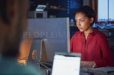 Buy stock photo Shot of a young woman working on a computer in an office in the evening