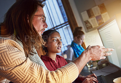 Buy stock photo Shot of two colleagues talking over a computer in an office late in the evening