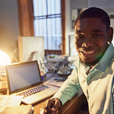 Buy stock photo Portrait of a smiling young man working on a laptop in an office in the evening