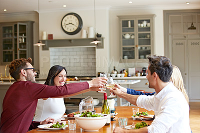 Buy stock photo Shot of a group of friends toasting while enjoying a home-cooked dinner together