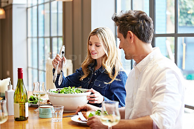 Buy stock photo Shot of a young couple enjoying a home-cooked dinner together