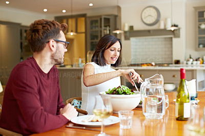 Buy stock photo Shot of a young couple enjoying a home-cooked dinner together