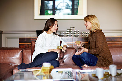 Buy stock photo Shot of a mother and her adult daughter drinking wine and chatting together on a sofa in her living