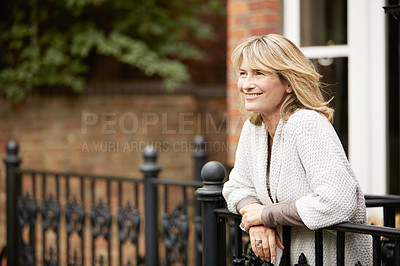 Buy stock photo Shot of a mature woman leaning against the railing of her front porch