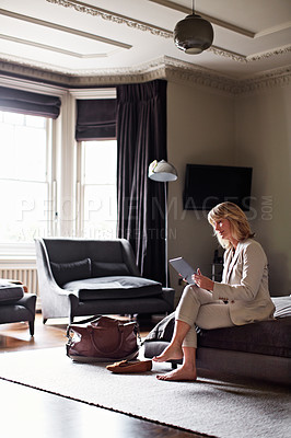 Buy stock photo Shot of a mature businesswoman sitting on a hotel bed using a digital tablet