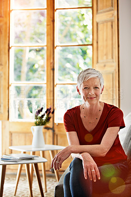 Buy stock photo Portrait of a smiling mature woman relaxing on her sofa at home