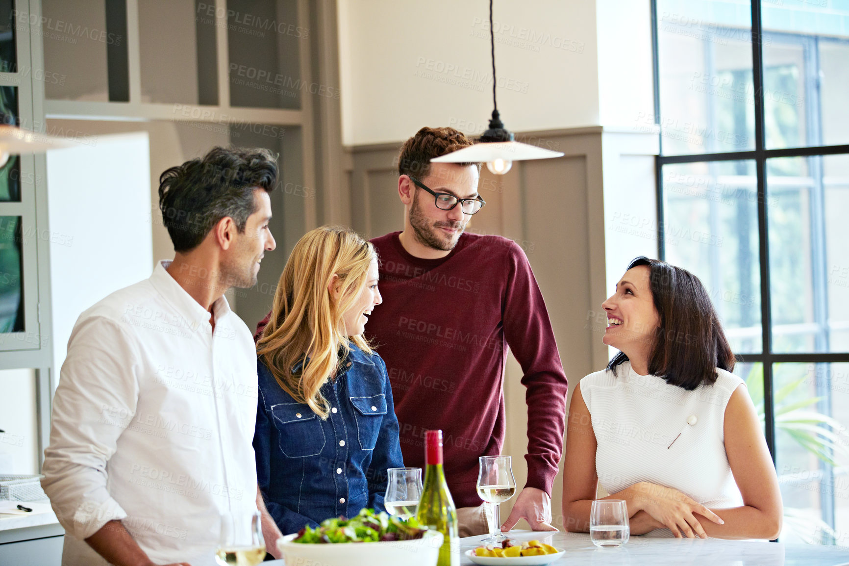 Buy stock photo Shot of a group of friends talking and drinking wine while preparing a meal together