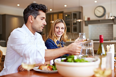Buy stock photo Shot of a young couple enjoying a home-cooked dinner together