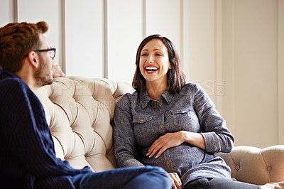 Buy stock photo Shot of a young expecting couple talking together while sitting on the sofa at home