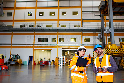Buy stock photo Shot of two warehouse workers talking together inside of a large warehouse