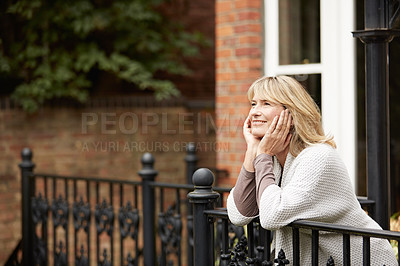 Buy stock photo Shot of a mature woman leaning against the railing of her front porch