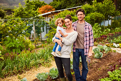 Buy stock photo Portrait of a smiling couple and their little daughter standing in their organic garden