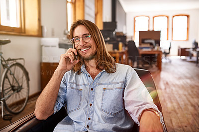 Buy stock photo Shot of a young designer talking on his phone while sitting in an office
