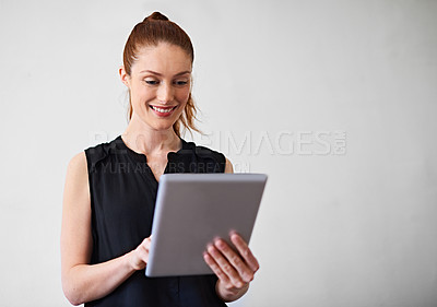 Buy stock photo Shot of a young woman using a digital tablet against a gray background