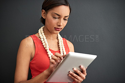 Buy stock photo hot of a young woman using a digital tablet against a gray background