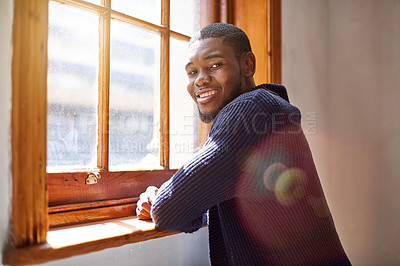 Buy stock photo Portrait of a smiling young man leaning on a window sill