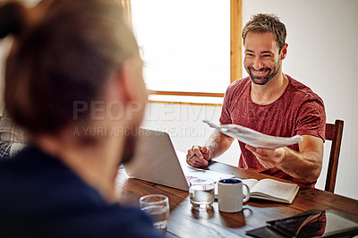 Buy stock photo Shot of man handing documents to a coworker while sitting at a table in an office